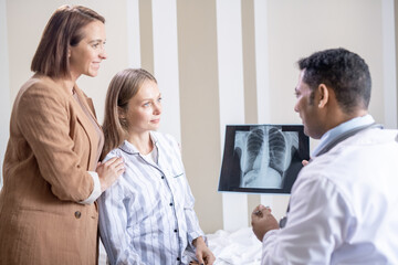 Fototapeta premium Confident radiologist with lung x-ray looking at his patient and her friend