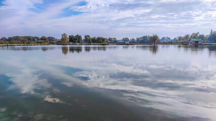 Fototapeta premium Sunny day on the perfect lake. Autumn lake with reflection on the water. Cloudy sky in the sunny day.