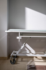 Empty medical cart standing by wall and window in hospital chamber or corridor