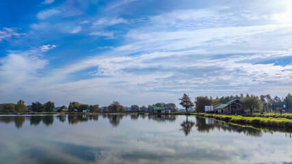 Sunny day on the perfect lake. Autumn lake with reflection on the water. Cloudy sky in the sunny day.