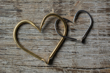 Fishing hooks set in the shape of a heart on a wooden background.