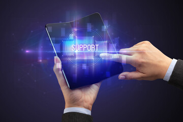 Businessman holding a foldable smartphone with SUPPORT inscription, new technology concept