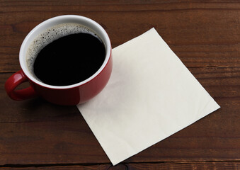 Obraz na płótnie Canvas A mug of coffee with a blank napkin on a rustic wood table. Room for your copy or doodle.