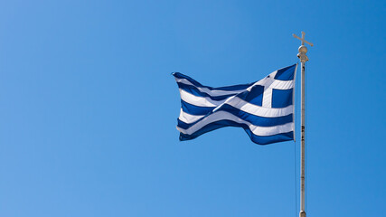 Waving national flag of Greece with clear blue sky in the background. 