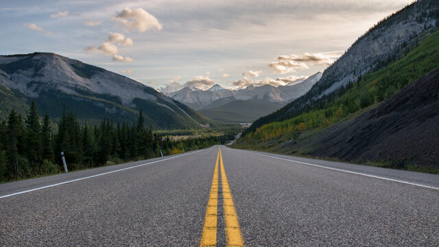 Road to the rocky mountains at sunset. Yellow road paint lines wallpaper. Empty deserted street in the countryside rural Alberta valley wallpaper