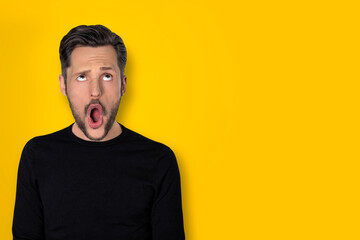 Portrait of young man with a wow expression on a yellow background
