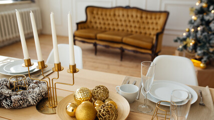 New Year's table setting. Christmas wreath, candles, tree. Beautiful festive interior