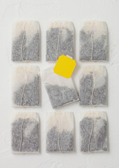 Black tea in teabags with yellow label on white.