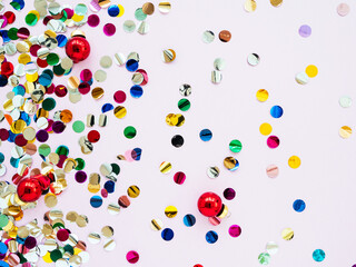 Multi-colored shiny round confetti on a pink background, top view, copy space, flat lay