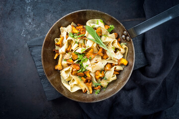 Traditional fried tagliatelle con galletti with mushrooms offered as top view in a rustic iron pan