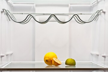 white fridge almost empty with a lime and lemon and a half.