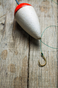 Hook and float prepared for fishing on a wooden background.