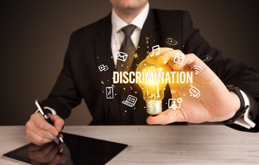 Businessman holding light bulb with DISCRIMINATION inscription, social media concept