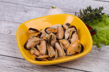 Pickled mussels in the bowl served pepper, garlic and salad
