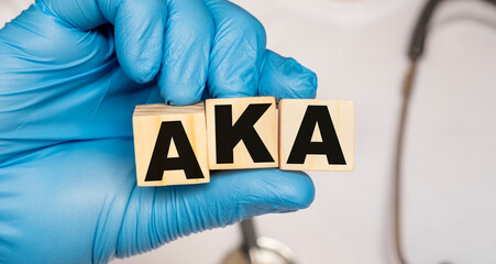 AKA Above the knee amputation. - word from wooden blocks with letters holding by a doctor's hands in medical protective gloves. Medical concept.