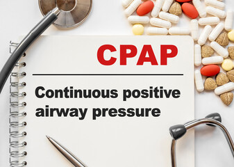 Page in notebook with CPAP Continuous positive airway pressure on white background with stethoscope...