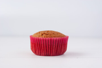 Single golden brown cake in a red capsule over white background