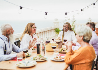 Cheerful senior people have dinner together oudoor on patio - Elderly multiracial friends