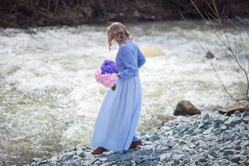 girl with a bouquet of hydrangeas walks on the shore, spring photo session