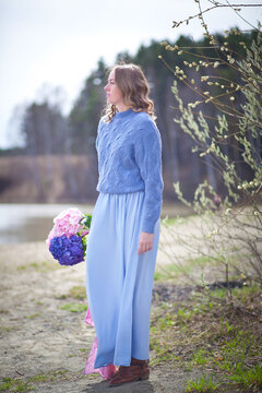 girl with a bouquet of hydrangeas walks on the shore, spring photo session