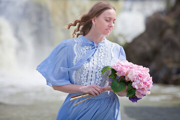 girl with a bouquet of hydrangeas walks on the shore, spring photo session