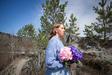 girl with a bouquet of hydrangeas walks on the shore, spring photo session