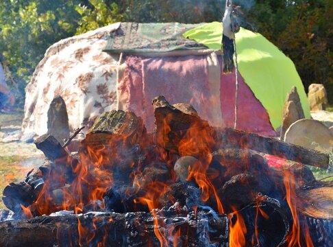 Bonfire with stones and inipi covered with blankets in the background.