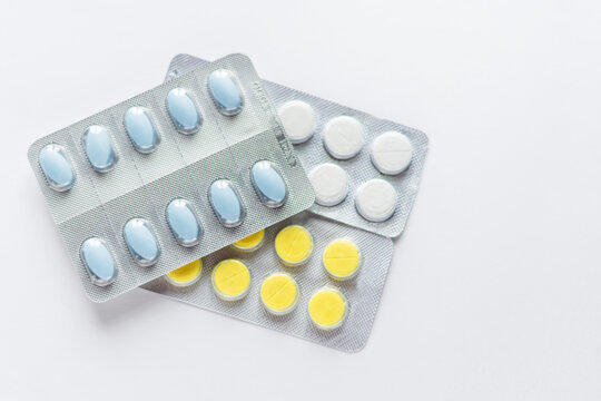 Blue, yellow and white tablets in blisters on white background