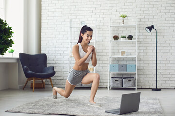 Smiling girl doing sports workout during online lesson on laptop at home