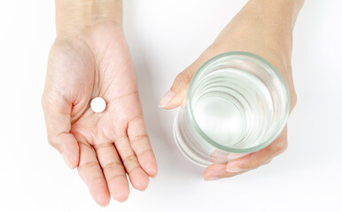 Healthcare and medical concept. Person holding pill in one hand and glass of water in the another hand. Flat lay.