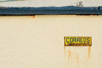 sign on the wall pointing to the post office on a yellow background with dirt