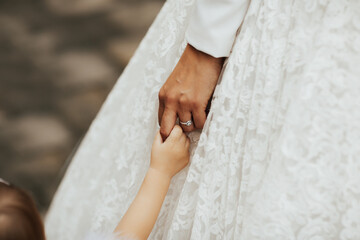 Close-up photo of a bride in luxury wedding dress holding child hand on her wedding day. Wedding...