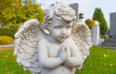 Sculpture of a little angel on a tomb in cemetery. Selective focus
