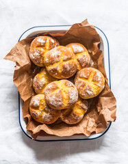 Fresh homemade pumpkin buns in a baking dish on a light background, top view