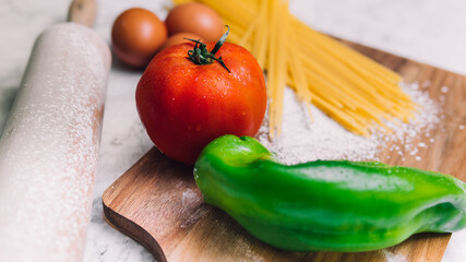 Tomato, green bell pepper and pasta on marble table