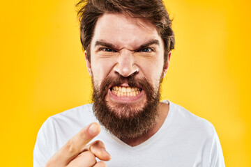 emotional bearded man gesturing with hands aggression discontent close-up yellow background