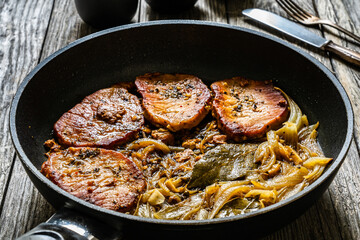 Pork steaks in frying pan with onion