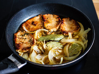 Pork steaks in frying pan with onion
