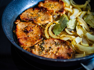 Pork steaks in frying pan with onion
