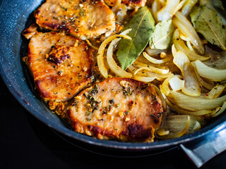 Pork steaks in frying pan with onion
