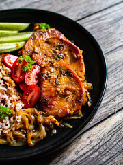 Roasted meat, buckwheat and pickled cucumbers on wooden table
