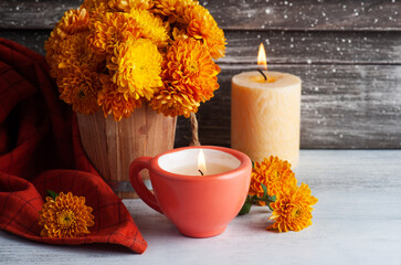 Lit aroma red candle and orange flowers