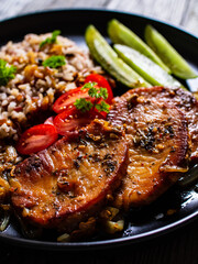 Roasted meat, buckwheat and pickled cucumbers on wooden table
