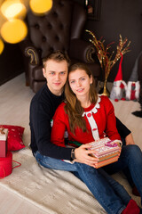 Young couple unpacking gifts on Christmas tree background.