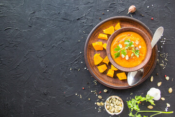 Delicious healthy pumpkin soup, herbs, and ingredients for the dish. Creative atmospheric decoration