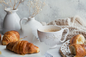 Delicious breakfast with fresh croissants and cup of coffee on a white wooden background. Delicious Baking