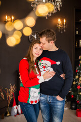 Portrait of young couple in Christmas sweaters on the background of Christmas tree