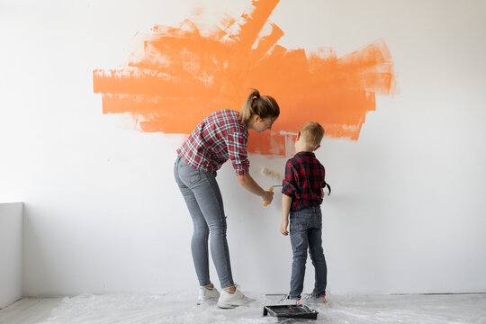 Mom And Son Are Painting The Wall With Orange Paint. Home Renovation Concept