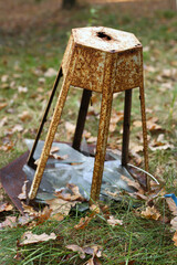 Old, rusty metal broken lantern, on the grass with autumn foliage in the park.