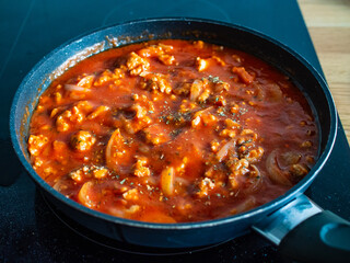 Pork nuggets frying in pan with tomato sauce and white onion